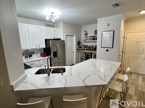 A kitchen with white cabinets and a marble island.