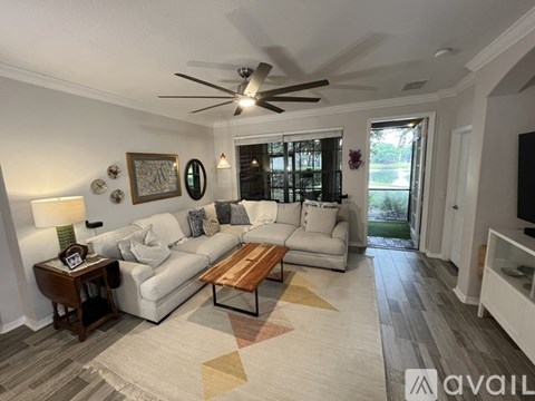 A living room with a white couch, a wooden coffee table, and a ceiling fan.