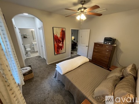 A bedroom with a bed, dresser, and a ceiling fan.