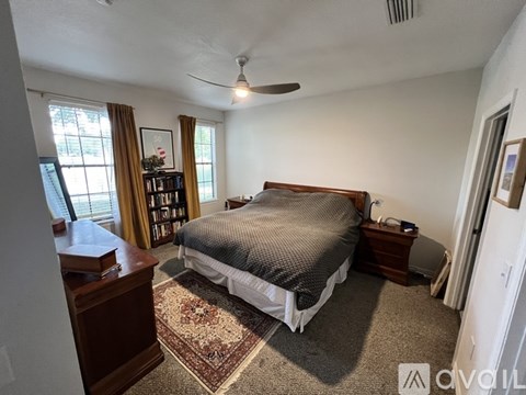 A bedroom with a bed, a dresser, and a ceiling fan.