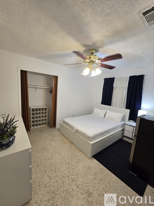 A bedroom with a bed, dresser, and ceiling fan.