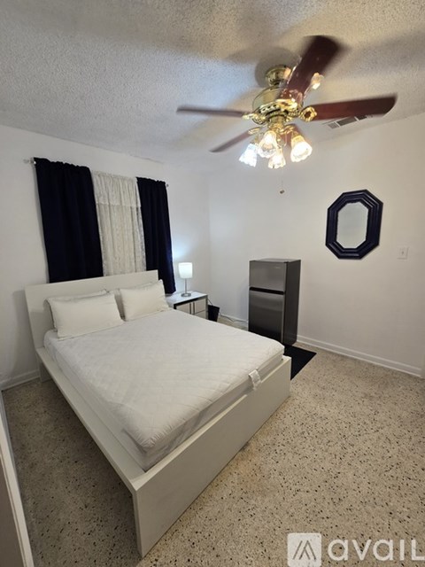 A bedroom with a bed, dresser, and ceiling fan.