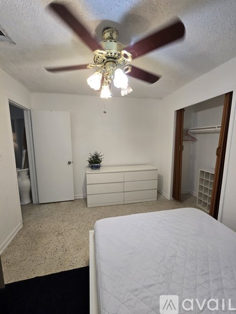 A bedroom with a bed, dresser, and ceiling fan.