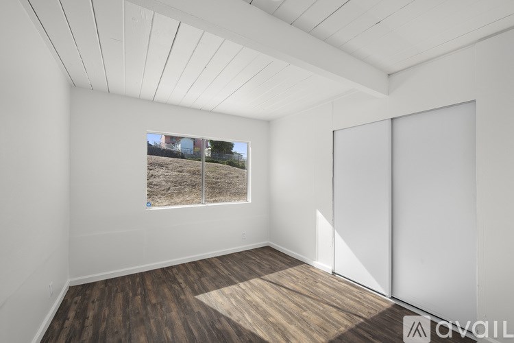 A room with wooden flooring and a window showing an outdoor view.