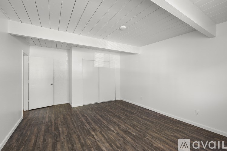 A room with wooden floors and white walls, with a ceiling that has a slanted design.