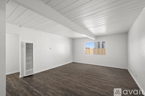 A spacious room with wooden flooring and white walls.
