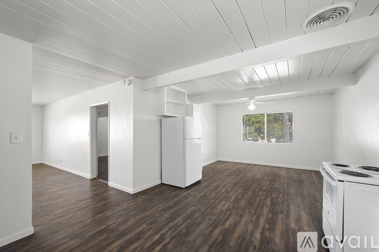 A spacious room with wooden floors and white walls.