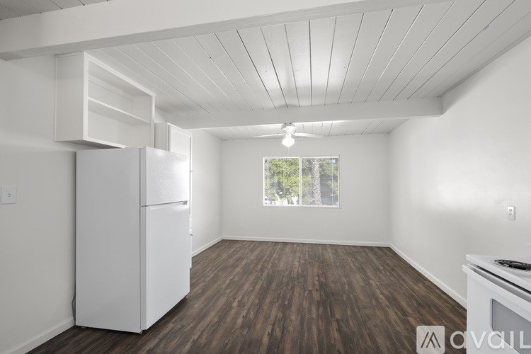 A kitchen with white appliances and wood flooring.