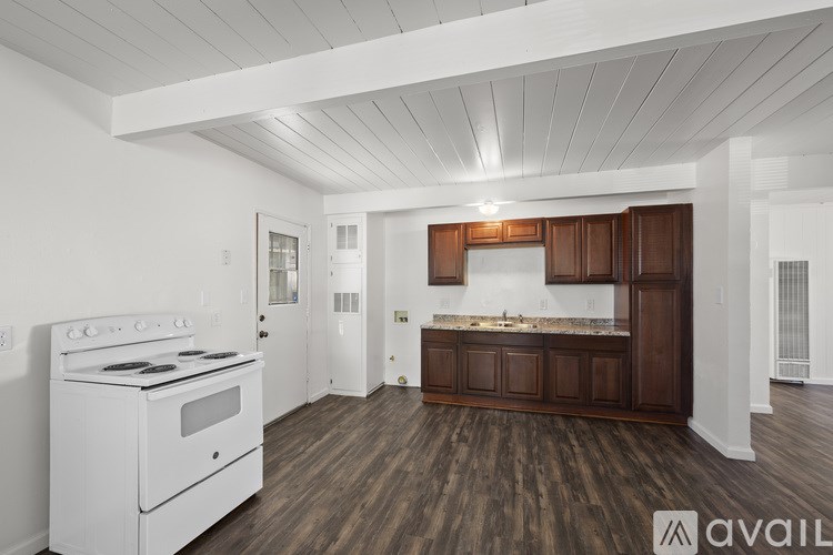 A kitchen with a white stove and wooden floors.
