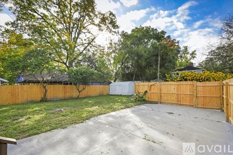A backyard with a wooden fence and a tree with yellow leaves.