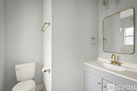A white toilet is next to a white sink with a gold faucet.