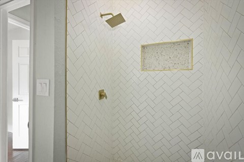 A bathroom with a white tiled wall and a gold shower head.