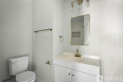 A white bathroom with a toilet, sink, and mirror.