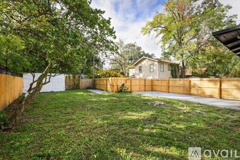 A backyard with a fence and a house in the background.
