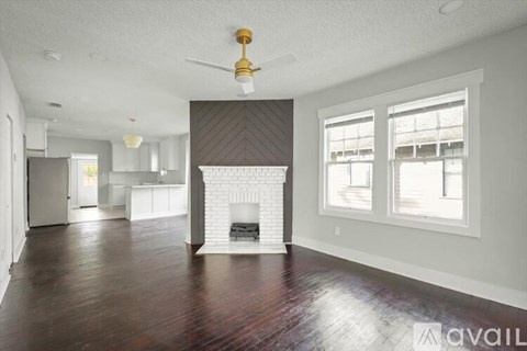 A living room with a fireplace and a ceiling fan.