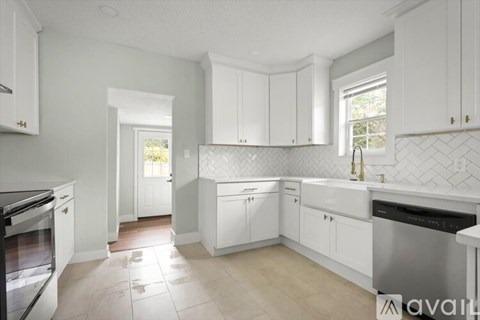 A kitchen with white cabinets and a tiled backsplash.