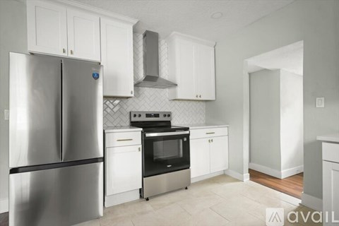 A kitchen with a stainless steel refrigerator and white cabinets.