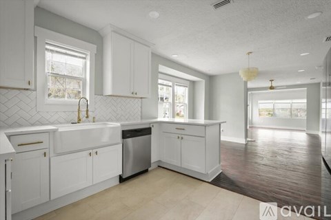 A kitchen with white cabinets and a wooden floor.