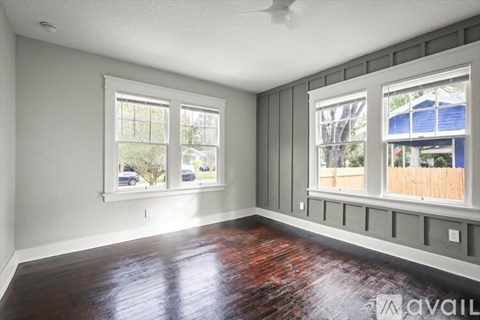 A room with a wooden floor and two windows.