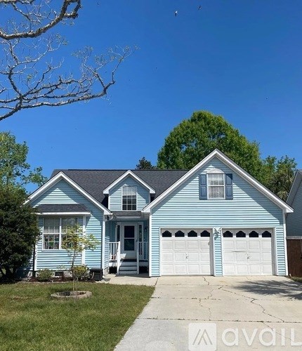 A blue house with a white garage door and a tree in front.