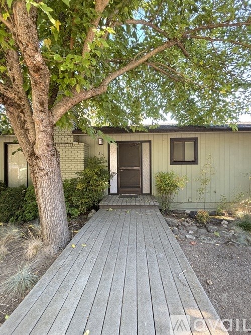 A wooden deck leads to a house with a brown door.