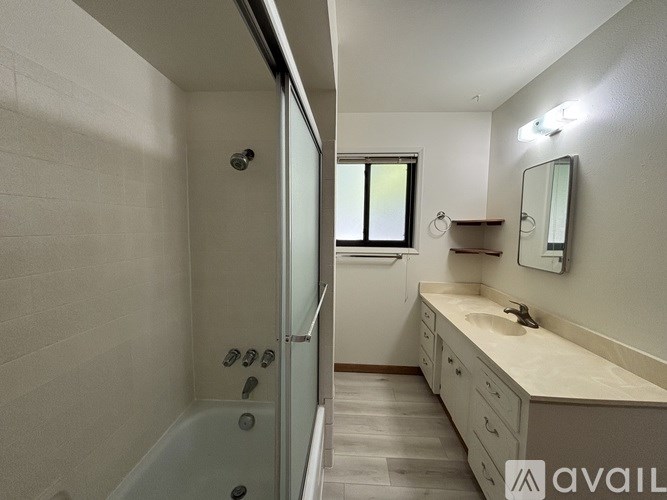 A bathroom with a tub, sink, and mirror.