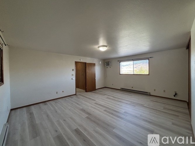 A spacious room with wooden flooring and a window.