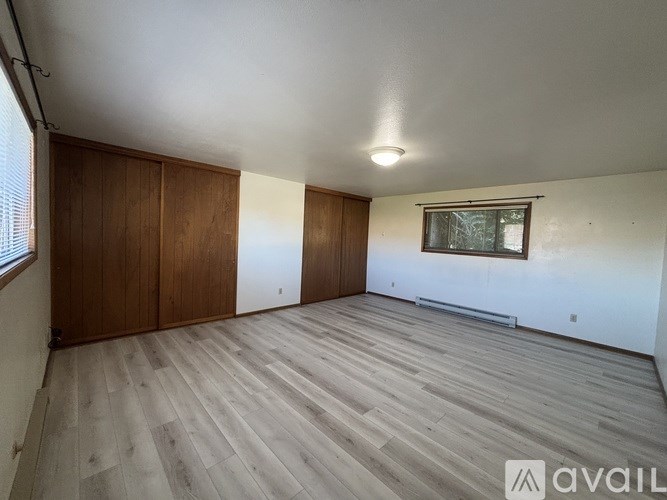 A room with wooden flooring and a window with blinds.