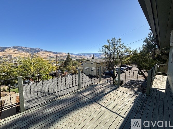 A wooden deck with a metal railing overlooks a residential area.