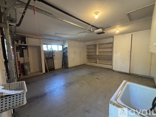 A large empty room with a sink and a window.