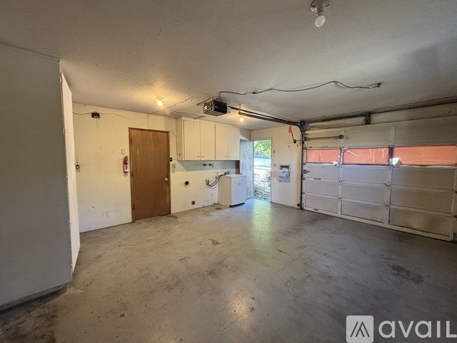 A spacious garage with a white cabinet and a brown door.