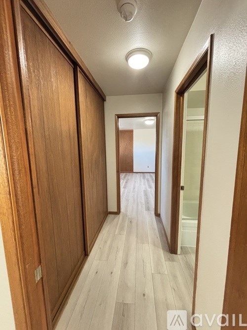 A long hallway with wood floors and wooden doors.