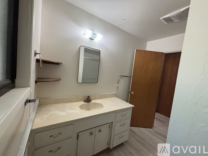 A bathroom with a sink, mirror, and wooden door.