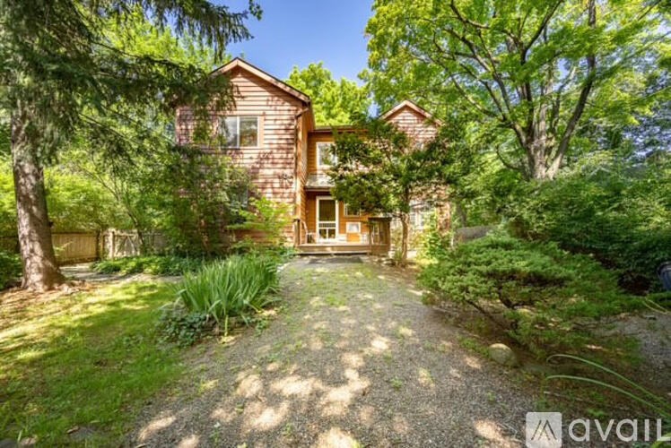 A house with a gravel driveway in front of it surrounded by greenery.