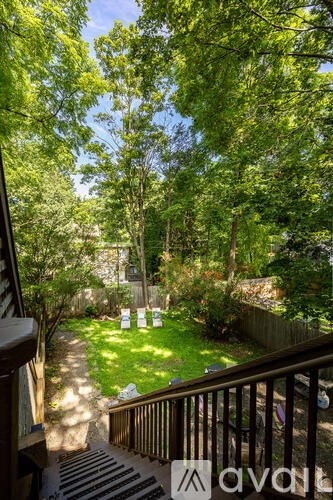 A view from a balcony looking down at a backyard with a lawn and trees.