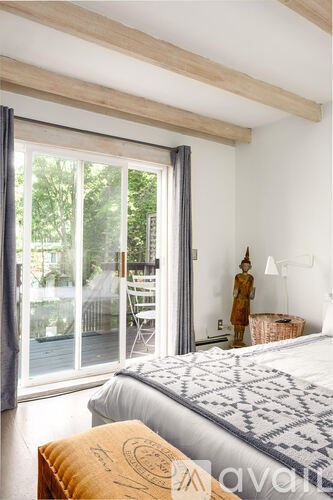 A bedroom with a bed, a chair, and a window with a view of the backyard.