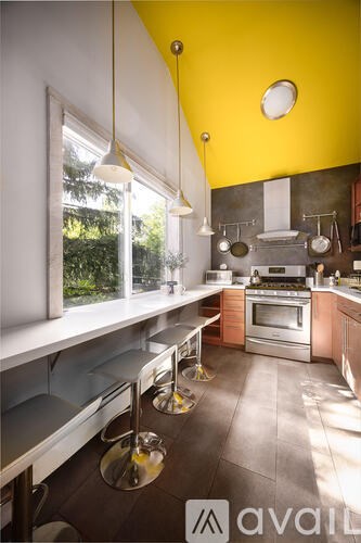 A modern kitchen with a yellow ceiling and stainless steel appliances.