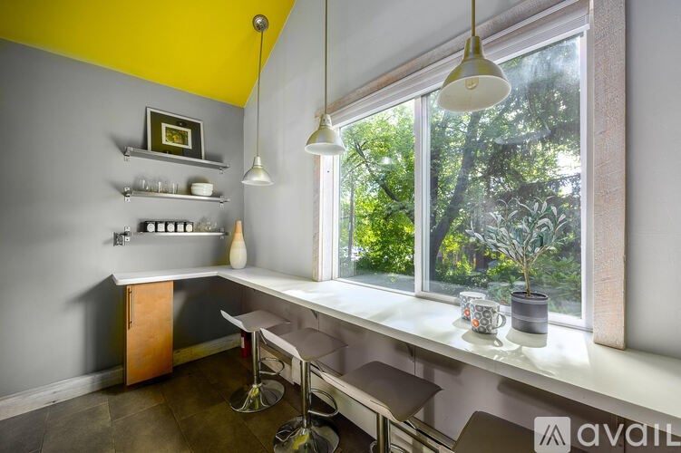 A kitchen with a yellow ceiling and a window overlooking a tree.
