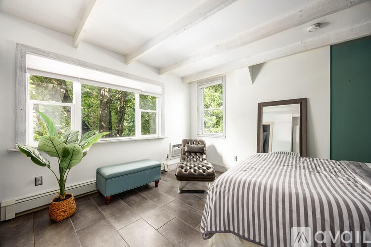 A bedroom with a bed, a bench, and a potted plant.