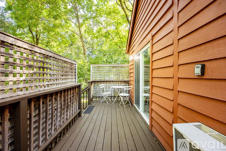 A deck with a table and chairs is surrounded by trees.