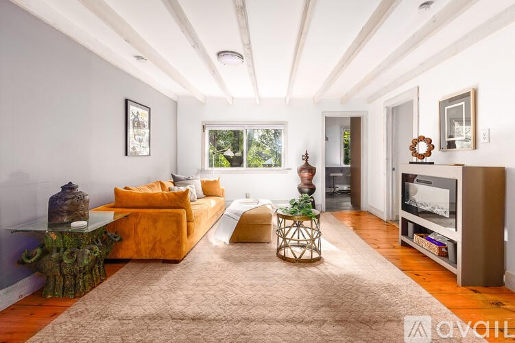 A living room with a yellow couch and a brown rug.