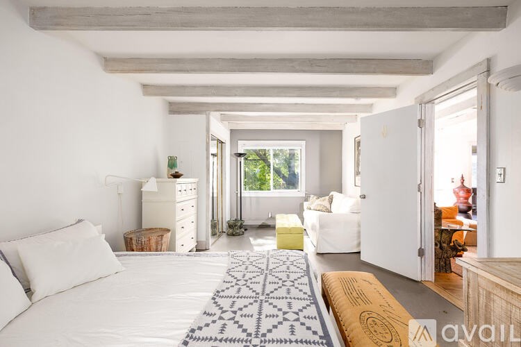 A bedroom with a white bed and a white dresser with a basket on top.