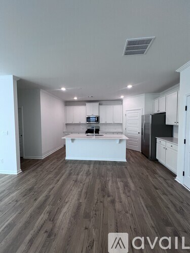 A modern kitchen with white cabinets and a wooden floor.