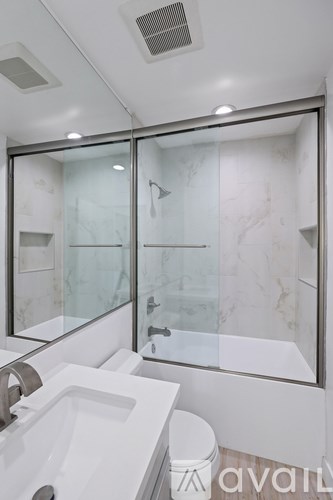 A modern bathroom with a glass shower door and a white sink.