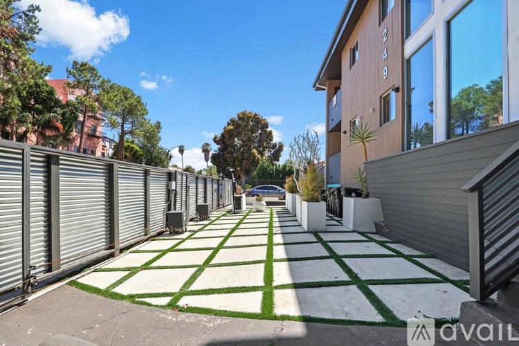 A long, narrow courtyard with a white and green patterned ground and apartment buildings on either side.