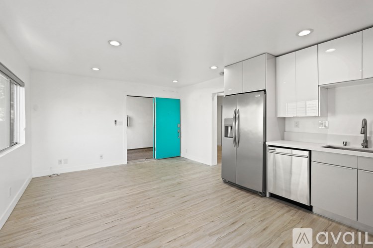 A modern kitchen with a teal accent door and stainless steel appliances.
