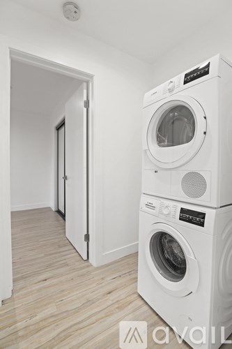 A white washing machine is in a room with a white door.