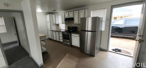 A kitchen with white cabinets and a refrigerator.