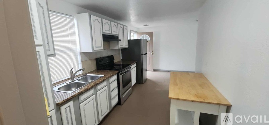 A kitchen with white cabinets and a wooden island.