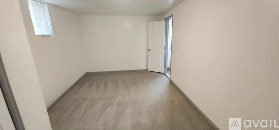 A room with a carpeted floor and a door leading to another room.